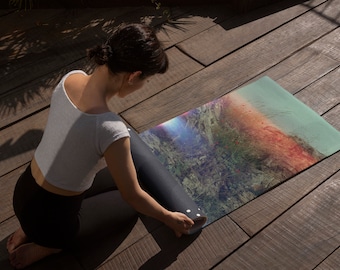 Puede incluir: Una persona enrolla una esterilla de yoga colorida con un diseño de paisaje. La esterilla tiene una combinación de colores azul, verde, naranja y rojo.