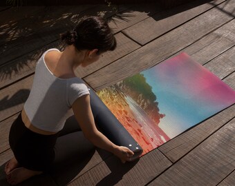 Puede incluir: Una persona enrolla una esterilla de yoga con una escena de playa colorida impresa en ella. La esterilla es negra con puntos blancos.