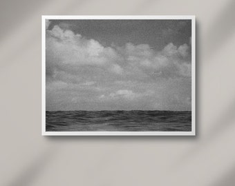 May include: A black and white photograph of a cloudy sky over a choppy ocean.