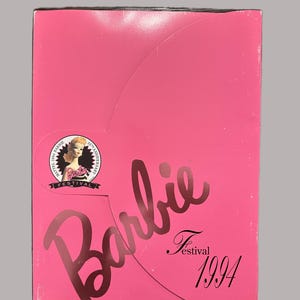 May include: A pink Barbie Festival 1994 box. The box features the Barbie logo in a cursive font and a small image of Barbie. The box also has the text "Festival 1994" in a script font.