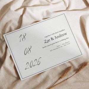 May include: A rectangular wedding invitation card with a thin gray border. The text reads: together with their families, Zoe & Andrew, invite you to join their wedding day, 5pm / Any Hotel, 123 Anywhere St., Any City. The date 18 08 2026 is printed.