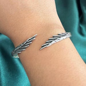 Op de afbeelding: Zilveren vleugelmanchet armband. De armband is open en heeft aan elke kant een vleugelontwerp.