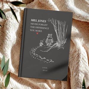 May include: A dark gray hardcover book with white text and illustrations. The cover reads "MRS. JONES NEVER FORGET THE DIFFERENCE YOU MAKE." A Winnie the Pooh and Piglet illustration is featured. The book is a thoughtful gift.
