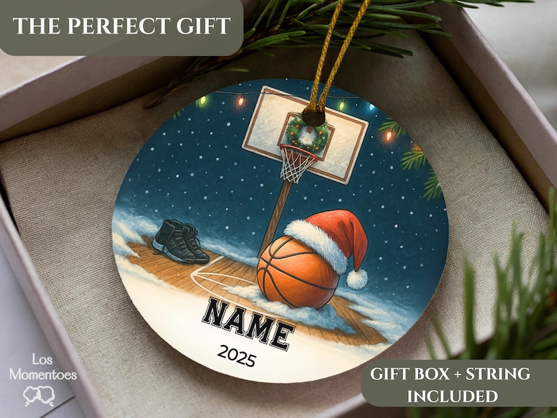 May include: Round Christmas ornament with a basketball theme. The ornament features a basketball wearing a Santa hat, a basketball hoop, and a pair of sneakers. The text "NAME" and "2025" are displayed on the ornament.