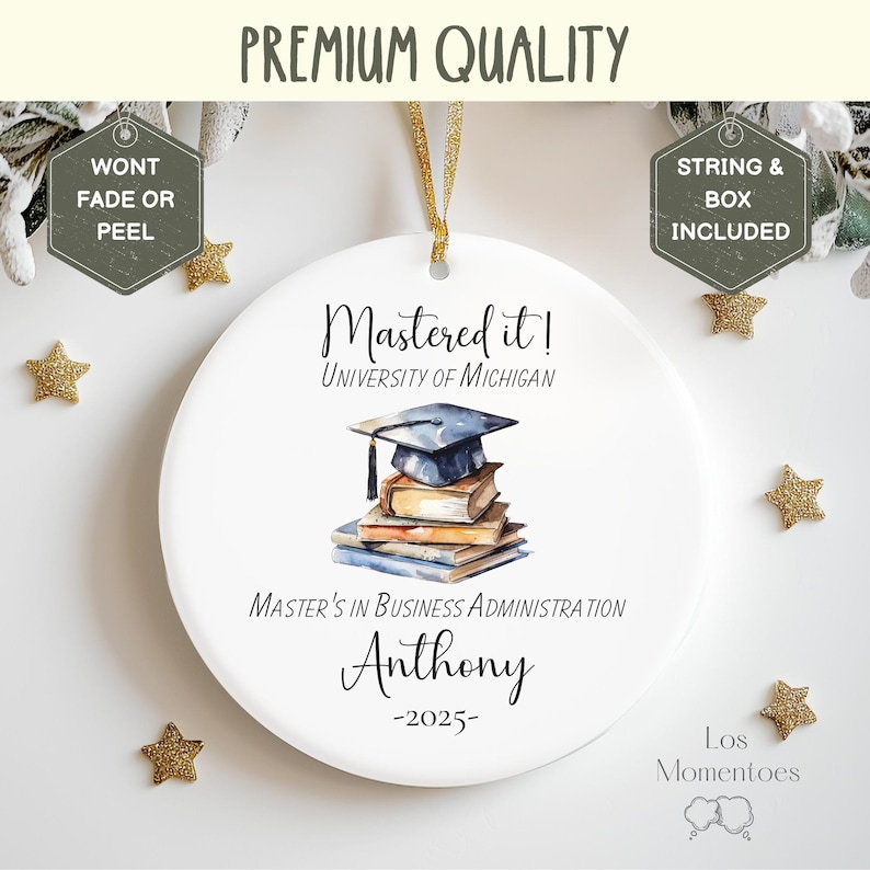 May include: White ceramic ornament with a blue graduation cap and books, text reads "Mastered it! University of Michigan Master's in Business Administration Anthony -2025- Los Momentoes"