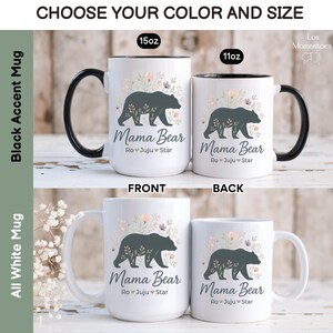 May include: White ceramic mugs with a black bear design and the text "Mama Bear." The mugs are available in 15oz and 11oz sizes, with options for black accent handles or all-white. Floral accents surround the bear illustration.