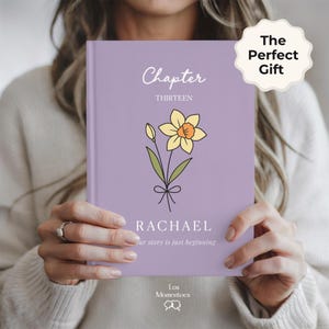 May include: A lavender-colored book with the words "Chapter Thirteen" and the name "Rachael" printed on the cover. A yellow daffodil illustration is also featured. The text "Our story is just beginning" is printed below the name.