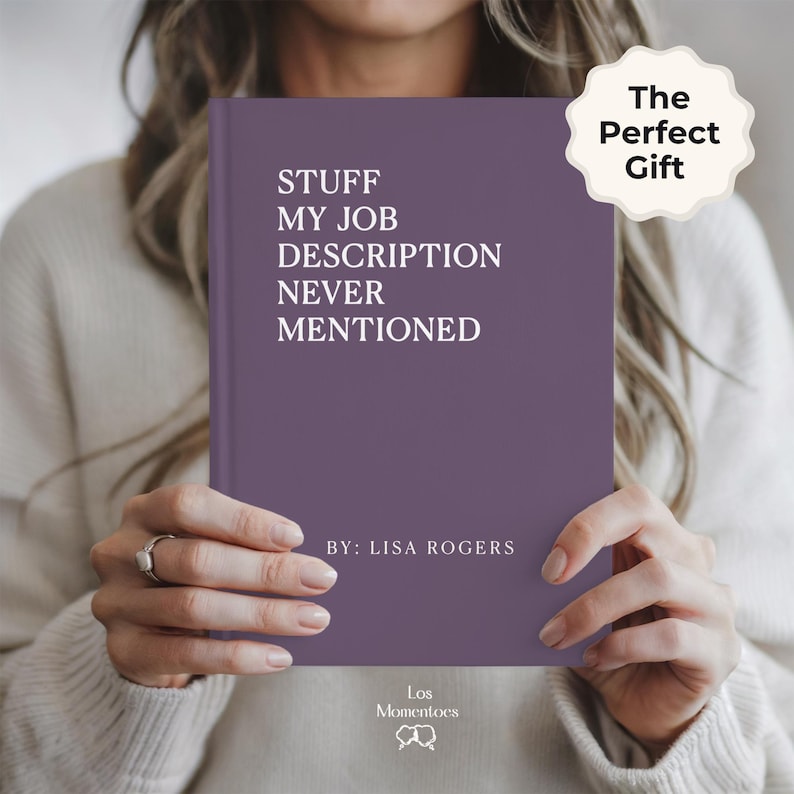 May include: A purple book with the text "STUFF MY JOB DESCRIPTION NEVER MENTIONED" in white. The book is held by a person. The text "The Perfect Gift" is on a white sticker. The author's name is "LISA ROGERS".