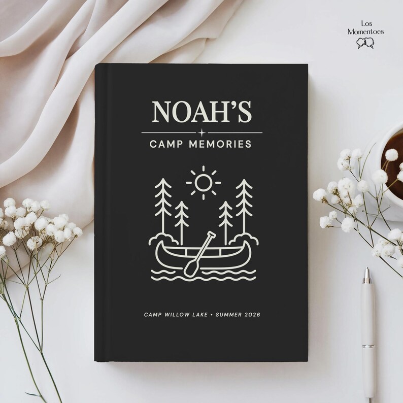 May include: A black journal featuring the text "NOAH'S CAMP MEMORIES" in white. The cover has a line drawing of a canoe, trees, and sun. The journal also includes the text "CAMP WILLOW LAKE - SUMMER 2026".