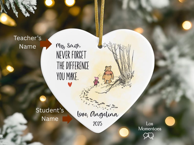 May include: A heart-shaped white ceramic ornament featuring a gold hanging ribbon. It displays a Winnie the Pooh and Piglet illustration with the text: Mrs. Smith, NEVER FORGET THE DIFFERENCE YOU MAKE, Love, Angelina, and the year 2025.