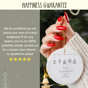 May include: White ceramic ornament with a black line drawing of Christmas ornaments hanging from a string. The text "Los Momentoes" is written below the ornaments.
