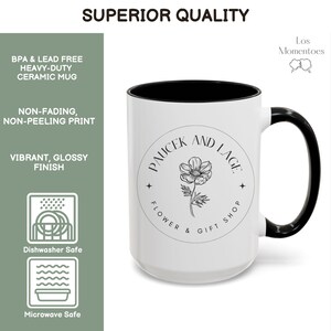 May include: A white ceramic mug with a black interior and handle. The mug features the text "PAUCEK AND LAGE FLOWER & GIFT SHOP" around a floral illustration. The mug is labelled as BPA & lead free, dishwasher and microwave safe.