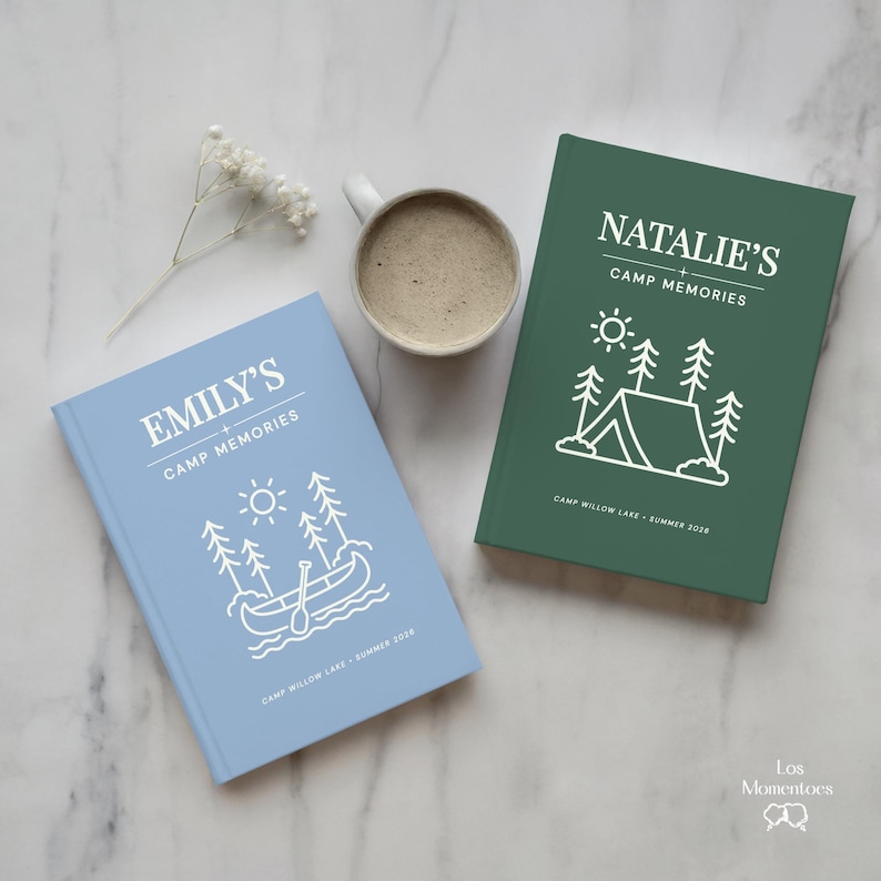 May include: Two personalised camp memory books, one light blue and one dark green, with white text and illustrations. The light blue book says "Emily's Camp Memories" and the green book says "Natalie's Camp Memories". A white mug of coffee sits between the books.