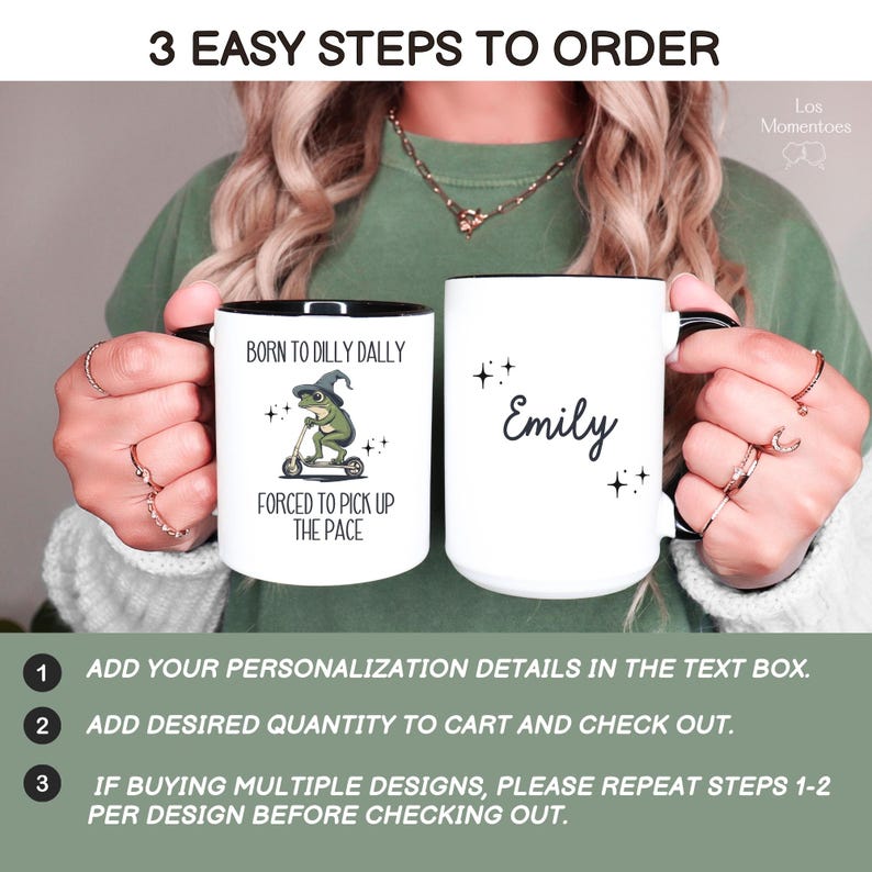 May include: Two white ceramic mugs with black rims. One mug has a green frog wearing a witch's hat riding a scooter with the text "Born to Dilly Dally, Forced to Pick Up the Pace". The other mug has the name "Emily" written on it.