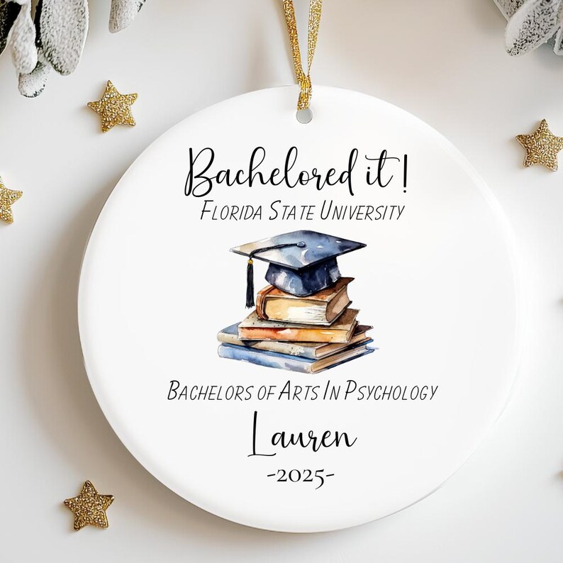 May include: White round ornament with the text "Bachelored it! Florida State University" and a watercolor illustration of a graduation cap on top of a stack of books. The text "Bachelors of Arts in Psychology" and the name "Lauren" are also included, along with the year "2025".