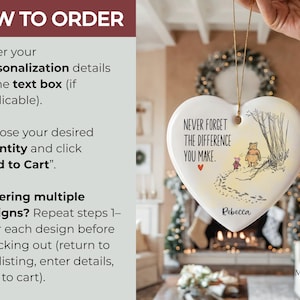 May include: A white heart-shaped ceramic ornament featuring a printed illustration of Winnie the Pooh and Piglet walking on a path. The text reads, "NEVER FORGET THE DIFFERENCE YOU MAKE." and "Rebecca" is printed at the bottom with a small red heart.
