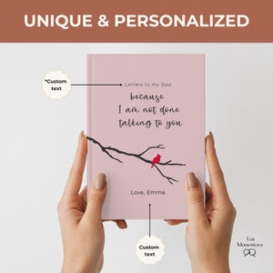 Op de afbeelding: Een roze notitieboek met de tekst "Letters to my Dad because I am not done talking to you." Een zwarte tak met een rode vogel is afgebeeld op de omslag. Het notitieboek wordt door twee handen vastgehouden. De tekst "Love, Emma" staat ook op de omslag.