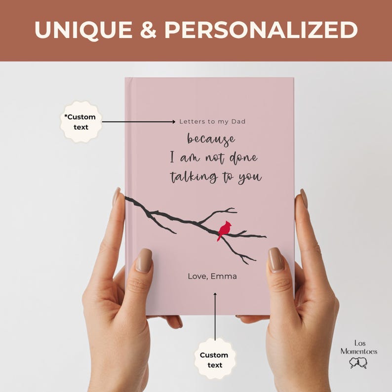Op de afbeelding: Een roze notitieboek met de tekst "Letters to my Dad because I am not done talking to you." Een zwarte tak met een rode vogel is afgebeeld op de omslag. Het notitieboek wordt door twee handen vastgehouden. De tekst "Love, Emma" staat ook op de omslag.