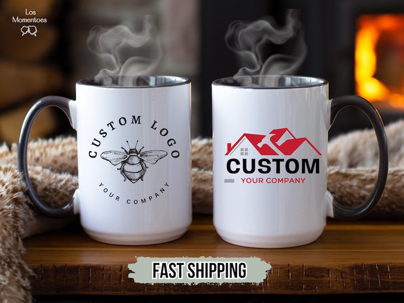 May include: Two white ceramic mugs with black handles and rims. One mug features a bee graphic with the text "CUSTOM LOGO YOUR COMPANY". The other mug has a red house and hammer graphic with the text "CUSTOM YOUR COMPANY". Steam rises from the mugs.