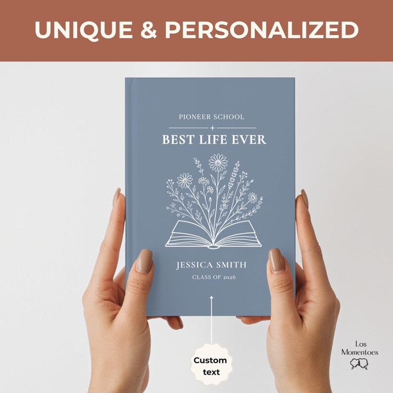 May include: A blue journal with the text "PIONEER SCHOOL BEST LIFE EVER" and the name "JESSICA SMITH" is held by two hands. The journal has a floral design and the words "UNIQUE & PERSONALIZED" are at the top.