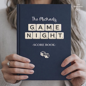 May include: A navy blue game night score book with the words "The Michaels GAME NIGHT -SCORE BOOK-" in white. The word "GAME NIGHT" is spelled out using Scrabble tiles. Two dice are at the bottom.