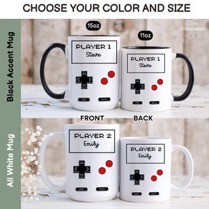 K&ouml;nnte beinhalten: Wei&szlig;e Keramikbecher mit einem Videospiel-Controller-Design. Eine Tasse hat einen schwarzen Henkel und Innenraum, die andere einen wei&szlig;en Henkel. Die Tassen sind mit "Player 1 Steve" und "Player 2 Emily" beschriftet. Der Text "W&auml;hlen Sie Ihre Farbe und Gr&ouml;&szlig;e" steht oben.