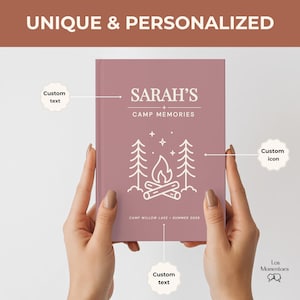 May include: A mauve-coloured personalised journal, held by two hands. The cover displays the text "SARAH'S CAMP MEMORIES" with a campfire and tree graphic. The text "CAMP WILLOW LAKE - SUMMER 2028" is also visible.