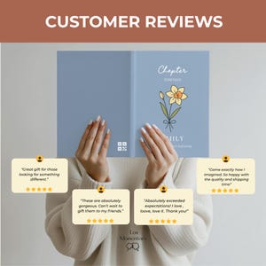 May include: A light blue journal with the text "Chapter Thirteen" and a daffodil illustration. The journal is held by a person. Customer reviews are displayed in the image.