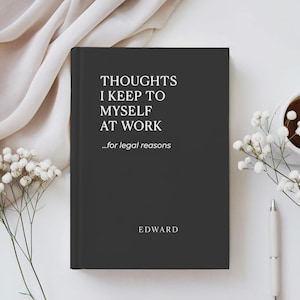 May include: A black hardcover journal with the text "THOUGHTS I KEEP TO MYSELF AT WORK ...for legal reasons" in white. The name "EDWARD" is printed at the bottom. The journal is on a white surface with a pen, a cup of coffee, and flowers.