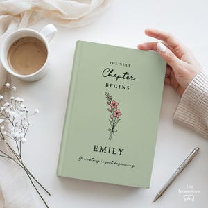 May include: A sage green book with the text "The Next Chapter Begins" and the name "Emily" in black script. A floral illustration with pink flowers is below the text. The phrase "Your story is just beginning" is at the bottom.