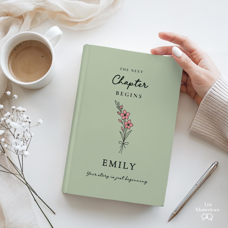 May include: A sage green book with the text "The Next Chapter Begins" and the name "Emily" in black script. A floral illustration with pink flowers is below the text. The phrase "Your story is just beginning" is at the bottom.