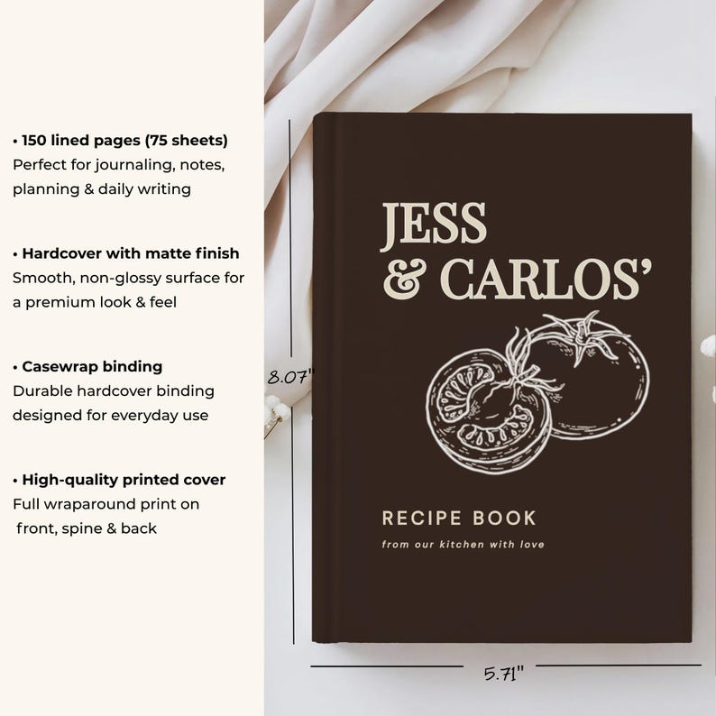 May include: A dark brown hardcover recipe book with a matte finish, featuring the text JESS & CARLOS' RECIPE BOOK from our kitchen with love and a white line drawing of two tomatoes. The book measures 8.07 inches by 5.71 inches with casewrap binding.
