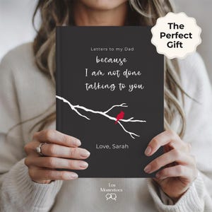 Op de afbeelding: Een zwart notitieboek met de tekst "Letters to my Dad" en de quote "because I am not done talking to you." Een witte tak met een rode vogel is afgebeeld op de omslag. Het notitieboek is gelabeld "The Perfect Gift."