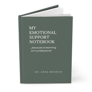 May include: A hardcover notebook with the text "MY EMOTIONAL SUPPORT NOTEBOOK" in white. Below the title is the phrase "...because screaming isn't professional." The author's name, "BY: ANNA MUENCH," is at the bottom. The cover is a muted green color.