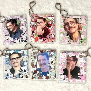 May include: Six square acrylic keychains featuring photographs of a man with a moustache and glasses. Each keychain is decorated with various colourful stickers, including cartoon characters, hearts, and food items, and includes a silver ball chain.