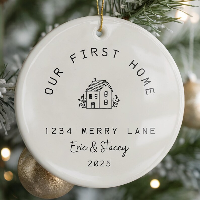 White ceramic ornament with black text that reads 'Our First Home' with a house icon and the address '1234 Merry Lane', names 'Eric & Stacey', and the year '2025'.  The ornament has a string for hanging.  The text 'Ships Fast!' is in the bottom right corner of the image.