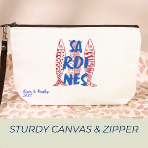 Sardines Mediterranean sailorcore personalized Zipper close canvas sardines makeup bag pencil pouch with bold blue and red sardine print and optional personalized name in script on cream coastal fabric. Sailorcore sardinecore and Mediterranean market girl aesthetic perfect for storing makeup pens and travel essentials and designed to coordinate with the large coastal sardines tote bag sold separately.