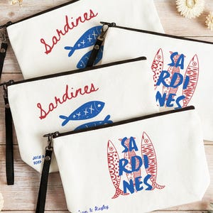 Sardines Mediterranean sailorcore personalized Zipper close canvas sardines makeup bag pencil pouch with bold blue and red sardine print and optional personalized name in script on cream coastal fabric. Sailorcore sardinecore and Mediterranean market girl aesthetic perfect for storing makeup pens and travel essentials and designed to coordinate with the large coastal sardines tote bag sold separately.
