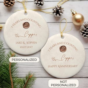 May include: Two white ceramic ornaments with a copper anniversary theme. One ornament is personalized with the names Jake & Sophia and the date 10.07.2017. The other ornament says "7 Years and Counting Copper Happy Anniversary".