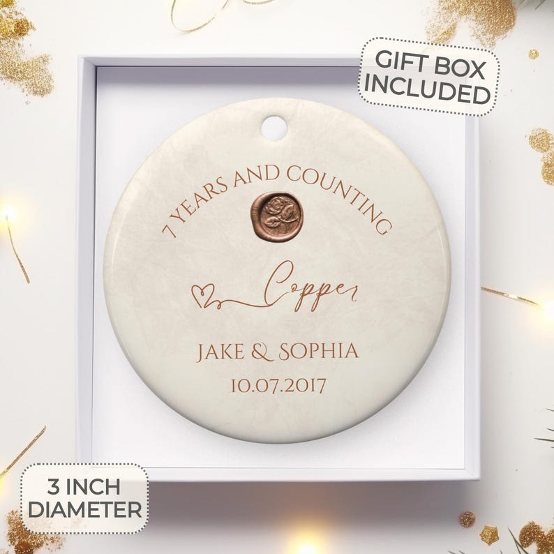 May include: A white ceramic ornament with a copper-colored inscription that reads "7 Years and Counting Copper Jake & Sophia 10.07.2017". The ornament is 3 inches in diameter and comes in a gift box.