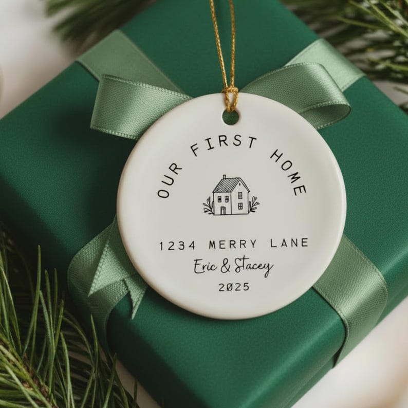 White ceramic ornament with black text that reads 'Our First Home' with a house icon and the address '1234 Merry Lane', names 'Eric & Stacey', and the year '2025'.  The ornament has a string for hanging.  The text 'Ships Fast!' is in the bottom right corner of the image.