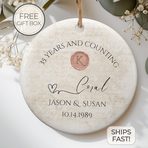May include: White ceramic ornament with a vintage design featuring the text "35 Years and Counting" with a wax seal initial "K" and the names "Jason & Susan" and the date "10.14.1989".