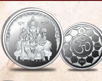 May include: Two silver coins, one featuring a depiction of the Hindu deity Ganesha, the other with the Om symbol. Both coins have the words "Shubh" and "Labh" inscribed on them.