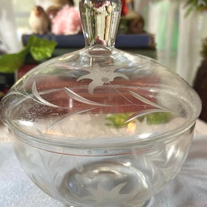May include: A clear glass sugar bowl with a lid. The bowl and lid are etched with a floral design.