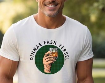 May include: White t-shirt with a green and black plaid circle design. The circle has the text "Dinnae Fash Yersel" and a hand holding a glass of whiskey.