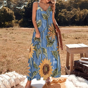 May include: A blue maxi dress with a floral print featuring sunflowers. The dress has a V-neckline and spaghetti straps.