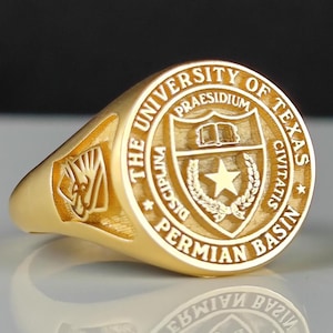 May include: A gold-colored class ring with the inscription "The University of Texas Permian Basin" and a shield with a star and a book.