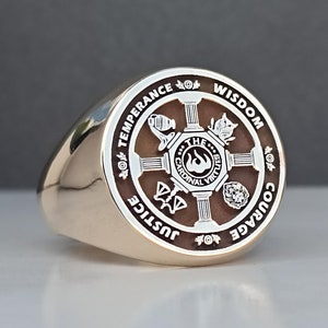 May include: A gold ring with a brown and white circular design featuring the words "The Four Cardinal Virtues" and the words "Justice, Temperance, Wisdom, Courage" around the outer edge.