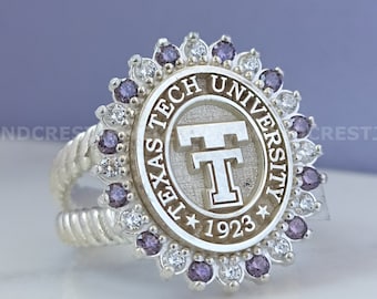 May include: A silver ring with a purple and white stone setting. The ring features the Texas Tech University logo and the words "Texas Tech University" and "1923".