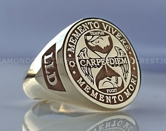 Könnte beinhalten: Ein goldener Siegelring mit einem braunen gravierten Design. Das Design zeigt eine Sanduhr mit Flügeln und den Text "Memento Vivere", "Tempus Fugit" und "Carpe Diem".